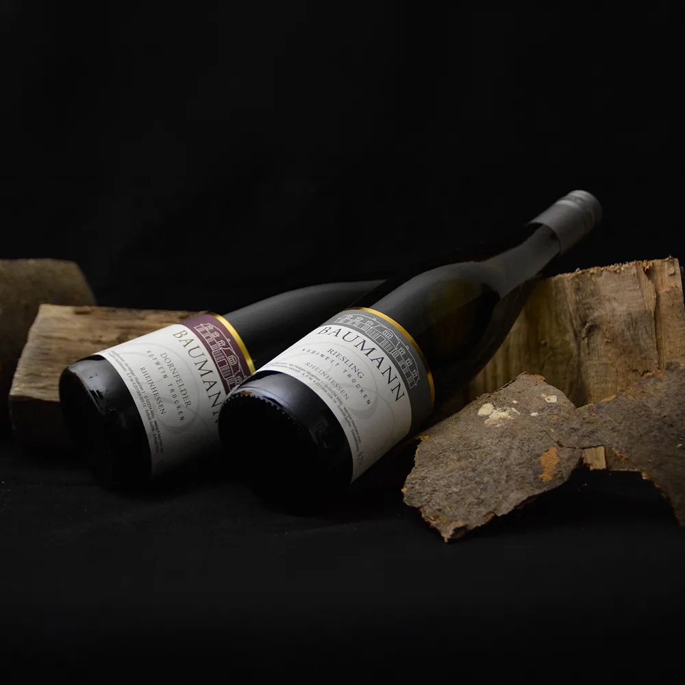 Zwei Weinflaschen vom Weingut Baumann zwischen Holzscheiten