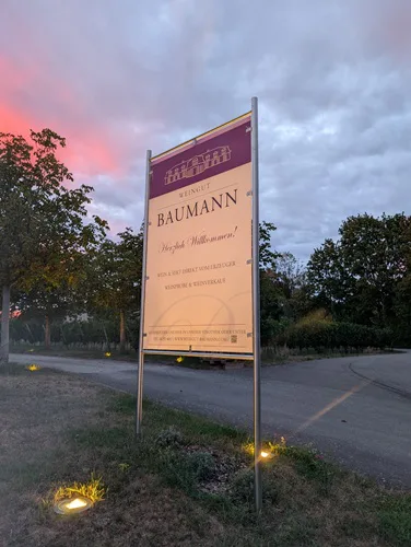 Willkommensschild des Weinguts Baumann in der Abenddämmerung