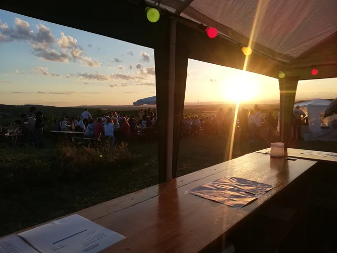 Blick aus dem Ausschankzelt auf die Gäste im Abendlicht